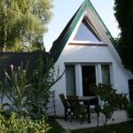 Wohnhaus mit Dreiecksfenster, Terrasse und Garten. Holztisch und Stühle vor der Tür.