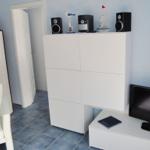 Wohnraum mit weißen Möbeln, Fernseher und Dekorationsgegenständen.