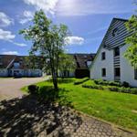 Haus mit gepflastertem Weg und grünem Rasen unter blauem Himmel.