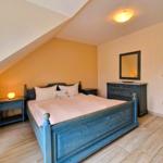 Schlafzimmer mit Bett, Nachttisch und Schrank unter schrägem Dach.