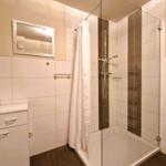 Badezimmer mit Dusche, Spiegelschrank und Waschtisch.