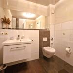 Badezimmer mit Waschbecken, Spiegel, Toilette und dunklem Boden