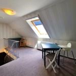 Dachgeschosszimmer mit Tisch, Stühlen und Dachfenster.