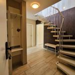 Eingangsbereich mit Treppe und Garderobe. Holzboden und moderne Beleuchtung.