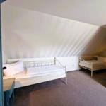 Zimmer mit zwei Betten unter schrägen Dachdecken und Teppichboden.