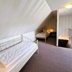 Zwei Betten in einem Dachgeschosszimmer mit gestreiften Wänden und Teppichboden.