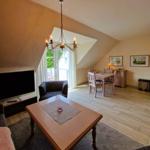 Wohn- und Essbereich mit TV, Tisch, Stühlen und Balkonzugang.