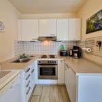 Küche mit weißen Schränken, Edelstahlherd und Holzdielenboden.