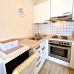 Küche mit weißen Schränken, Edelstahlherd und Spüle.