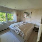 Schlafzimmer mit Doppelbett, Fenster und Wandbild.