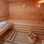 Sauna mit Holzbänken, Thermometer und Holzschale mit Besen.