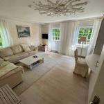 Wohnzimmer mit Sofa, Couchtisch und Fenstern mit weißen Vorhängen.