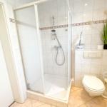 Bad mit Dusche, WC und Pflanze an der Wand.