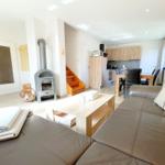 Wohn- und Essbereich mit Holztisch, Sofa und Kaminofen.