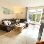 Wohnzimmer mit Ledersofa, Holztisch und Glastür zur Terrasse.