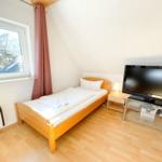 Ein Schlafzimmer mit Bett, Fernseher und Fenster.