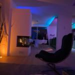 Wohnbereich mit Sessel, Kamin und Essbereich im Hintergrund.