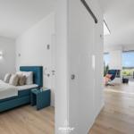 Schlafzimmer mit blauer Bettdecke und Blick auf Terrasse