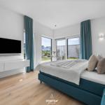 Schlafzimmer mit Bett, TV und Blick auf Balkon.