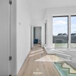 Flur mit Holzboden, Glasgeländer und Blick auf Balkon.