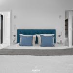 Schlafzimmer mit blauem Kopfteil und Fensterblick.