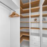 Schrank mit Holzregalen, Kleiderhaken und Schubladen im Schlafzimmer.