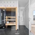 Dusche und Sauna mit Glaswand und Holzbank im modernen Badezimmer.