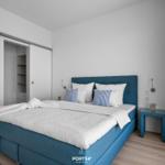 Schlafzimmer mit blauem Bett, Kleiderschrank und Nachttisch.