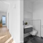 Flur mit Holzboden und Blick auf Balkon. Neben ihm befindet sich eine moderne Toilettenanlage.