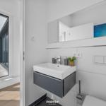 Badezimmer mit Waschbecken, Spiegel und Blick auf Balkon.