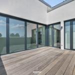 Terrasse mit Holzboden und großen Glasflügeltüren zu Innenräumen.