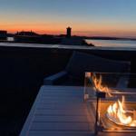Rooftop mit Feuerkamin und Blick auf Wasser bei Sonnenuntergang.