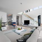 Wohnbereich mit Sofa, Fernseher und Treppe zur oberen Etage.