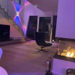 Wohnzimmer mit Kamin, Fernseher und moderner Treppe.