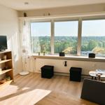 Wohnzimmer mit großem Fenster, TV und Sitzgelegenheiten.