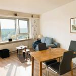 Wohn- und Essbereich mit Blick auf grüne Landschaft. Holztisch, Sofa und Fenster.