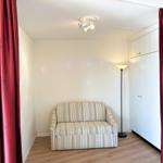 Zimmer mit Sofa, Kleiderschrank und roten Vorhängen.