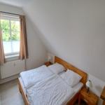 Doppelbettzimmer mit Holzbett, Nachttischen und Fenster mit Blick auf Grün.