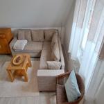 Wohnzimmer mit Ecksofa, Holztisch und Fenster mit Vorhängen.