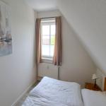 Schlafzimmer mit Bett, Nachttisch und Fenster unter Dachschrägen.