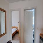 Halle mit Spiegel, Schlafzimmer und Bad. Küchenbereich mit Spüle und Geschirr.