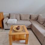 Wohnzimmer mit Ecksofa, Holztisch und Sideboard.