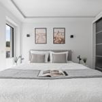 Schlafzimmer mit Bett, Wandbildern und Schwebetüren.