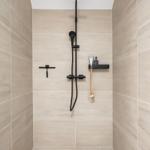 Duschkabine mit schwarzer Dusche und hellen Fliesen.