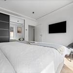 Schlafzimmer mit Doppelbett, Kleiderschrank und Fernseher an der Wand.