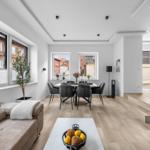 Wohn- und Essbereich mit Holzboden, Sofa, Esstisch und Blick auf Gebäude.