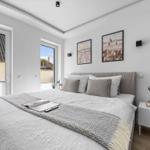 Schlafzimmer mit Bett, Nachttisch und Fenstern.