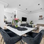 Essbereich mit Esstisch und Stühlen. Wohnzimmer mit Sofa und Fernseher.