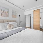 Schlafzimmer mit Bett, Wandbildern und Schiebetüren.