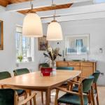 Esszimmer mit Holztisch, grünen Stühlen und zwei hängenden Lampen.